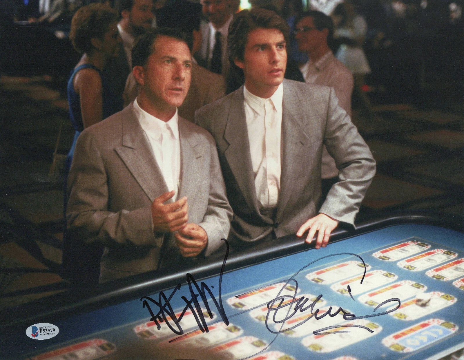 A colour Rain Man still of Dustin Hoffman and Tom Cruise standing at a casino table, signed by both across the blue felt in black marker.